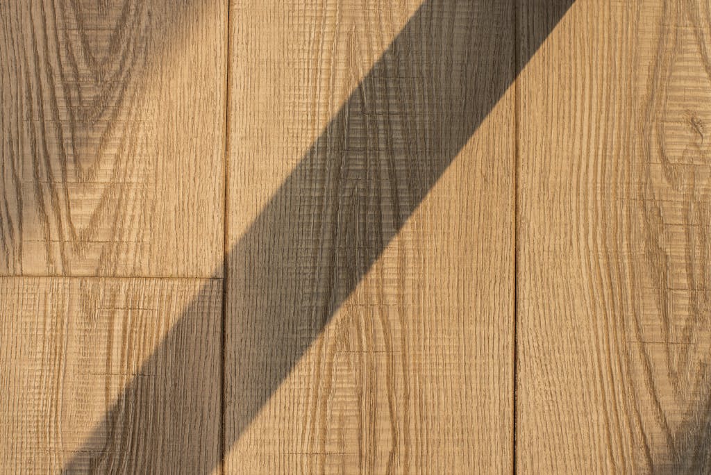 Detailed view of wooden floor planks with a dramatic shadow, showing natural texture.